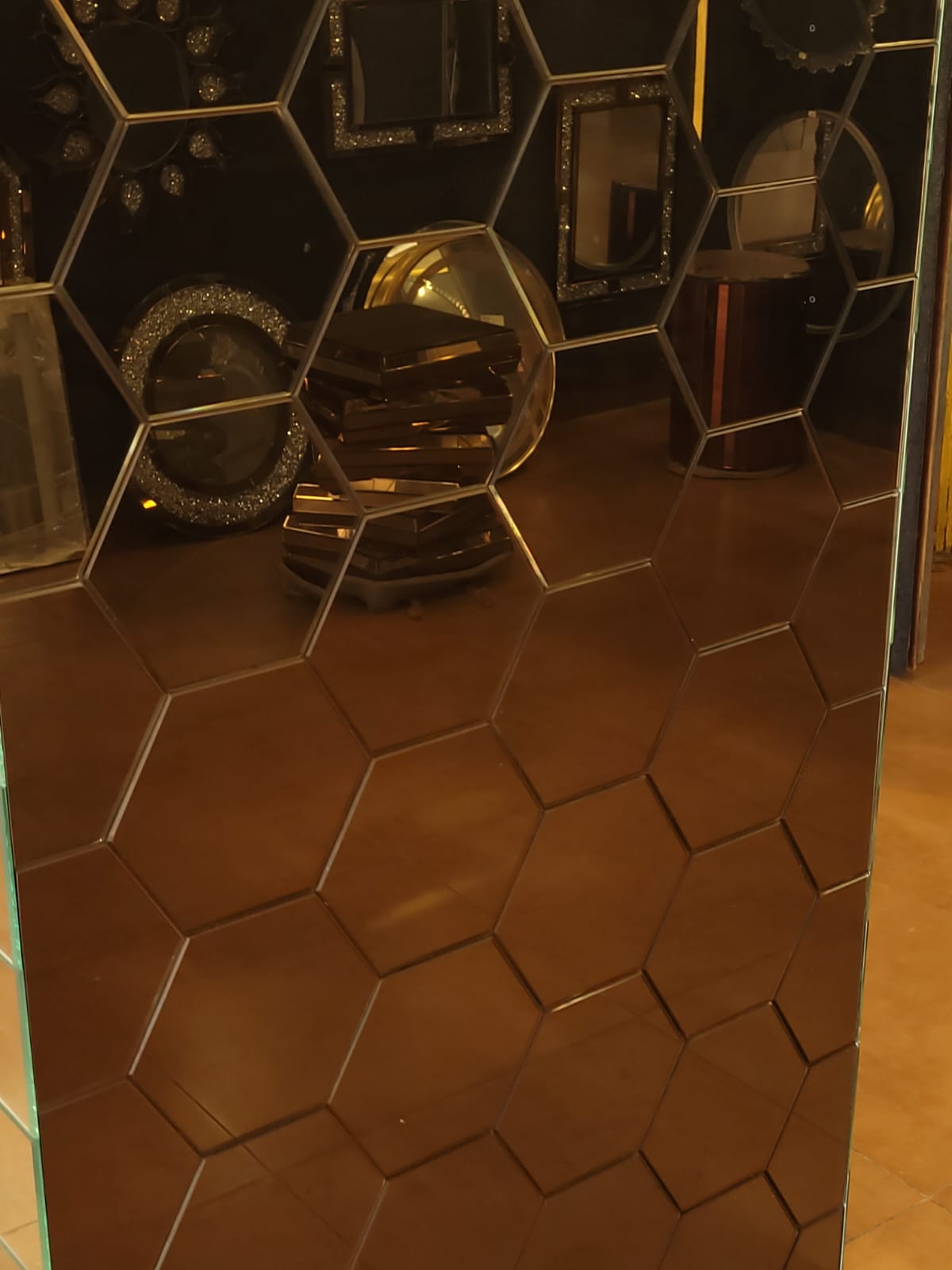 Hexagonal mirror panel — A bronze-toned mirror panel with an outlined honeycomb design.