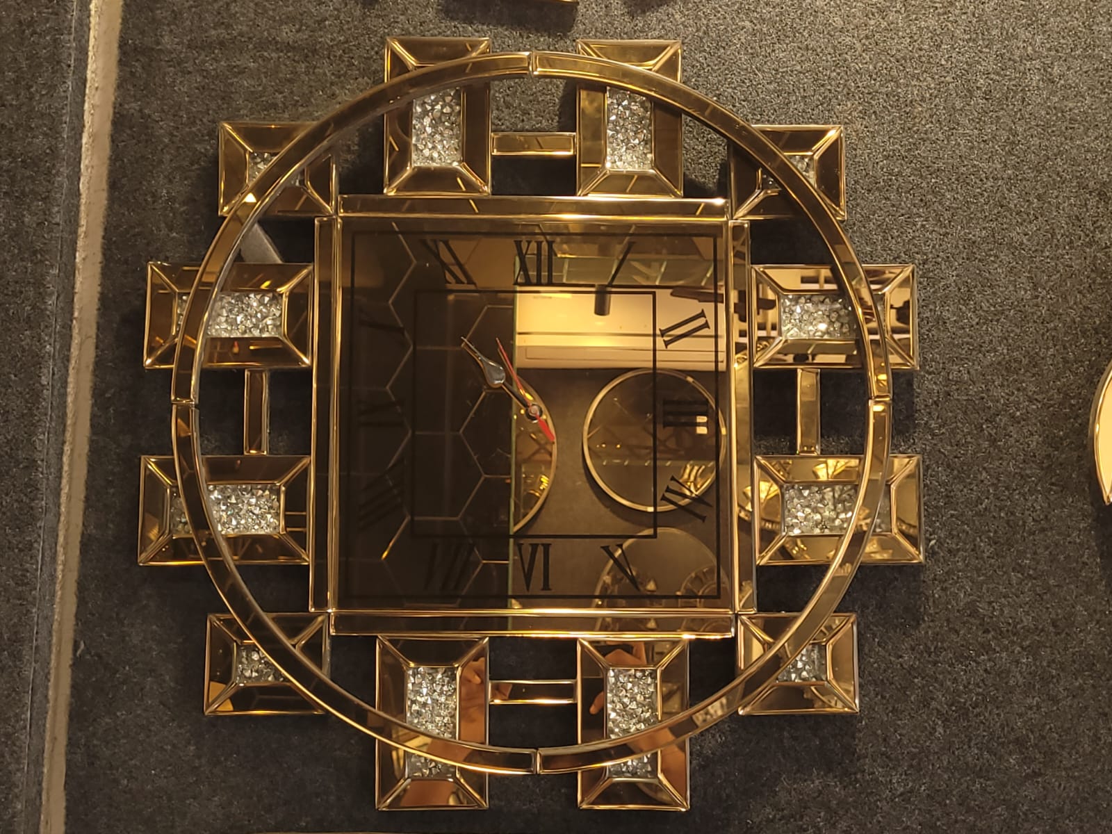 Square-face mirrored clock — A square clock face within an open circular geometric frame.