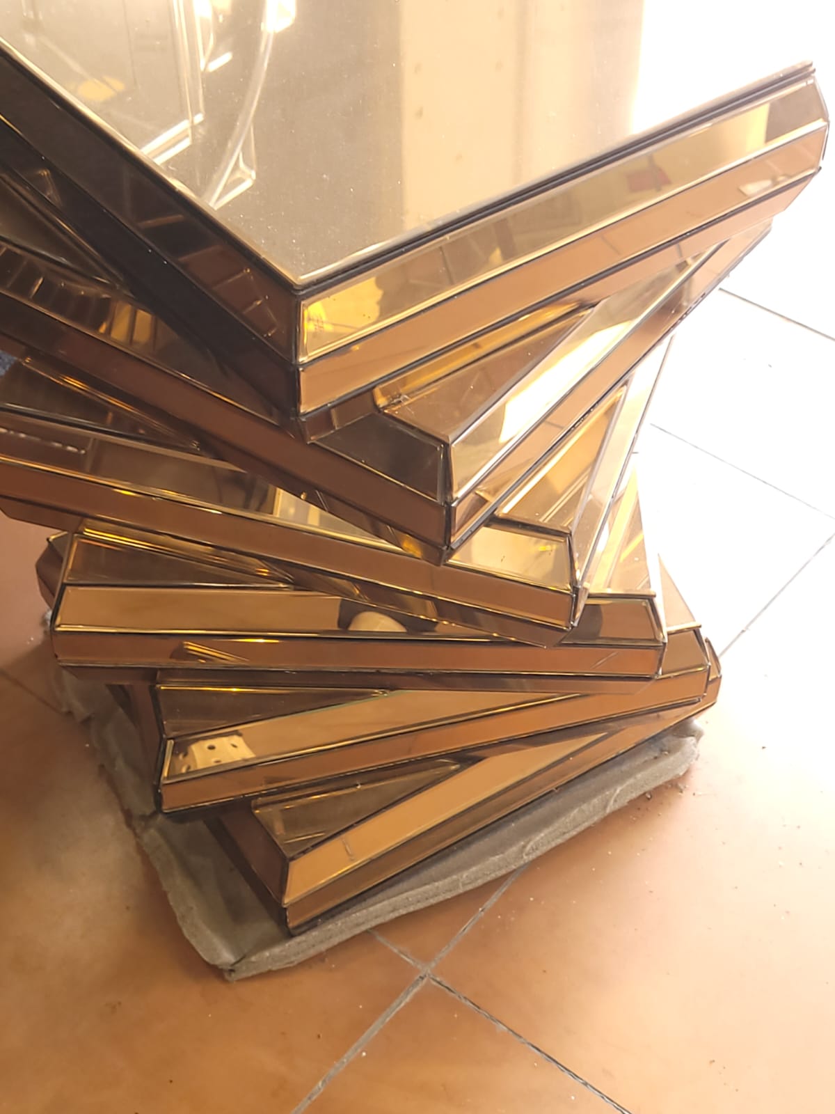 Twisted mirrored pedestal — Stacked mirrored planes form a sculptural, twisting pedestal.